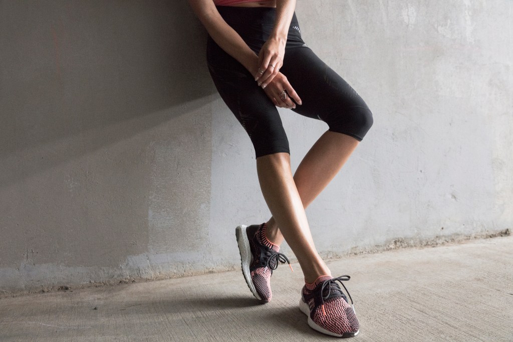 Mulher encostada na parede com roupa fitness e tênis Adidas