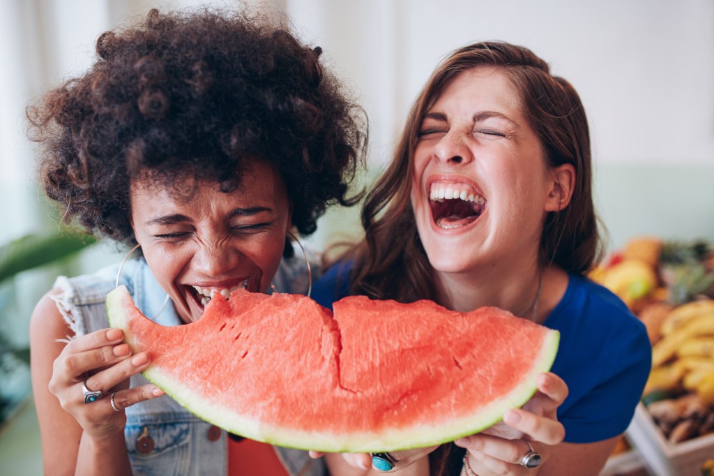 Mulheres rindo e comendo melancia