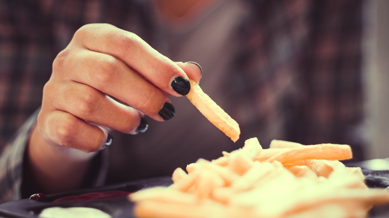 Mulher comendo batata frita