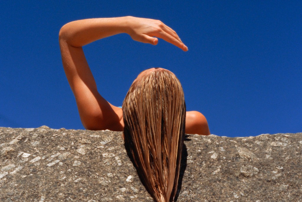 Mulher deitada na pedra com o cabelo molhado