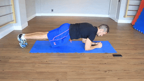 Boa Forma – prancha com rotação de quadril Homem em posição de prancha movimentando os quadris sobre um tapete de exercícios