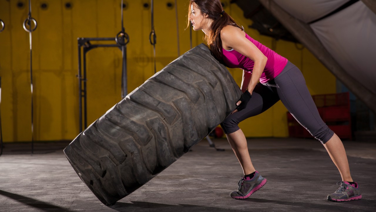 Mulher virando pneu no treino de crossfit - Como funcionam os treinos boot camp