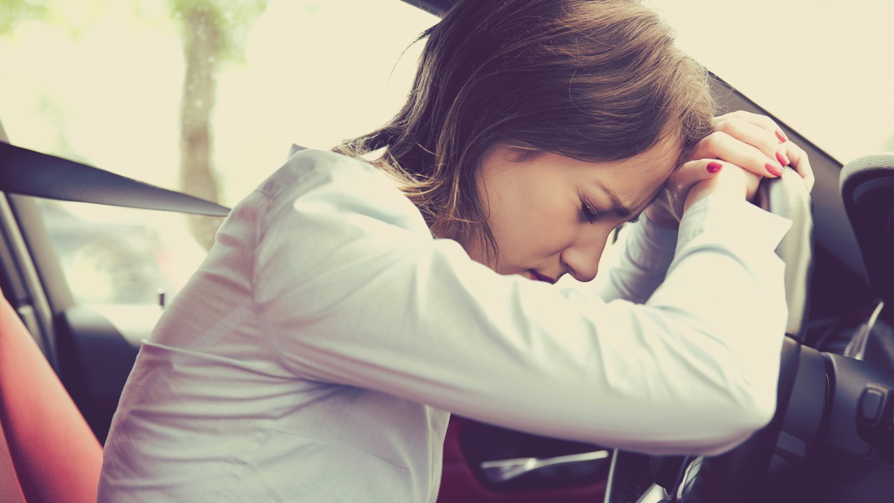 Mulher dentro do carro deitada no volante