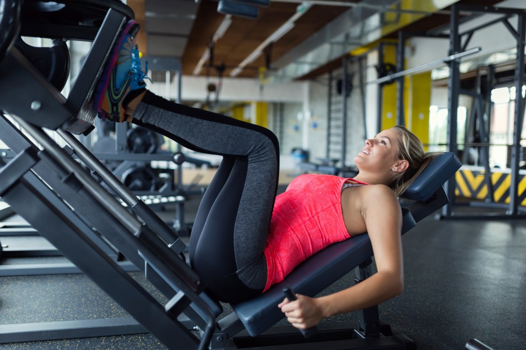 Mulher fazendo leg press na academia