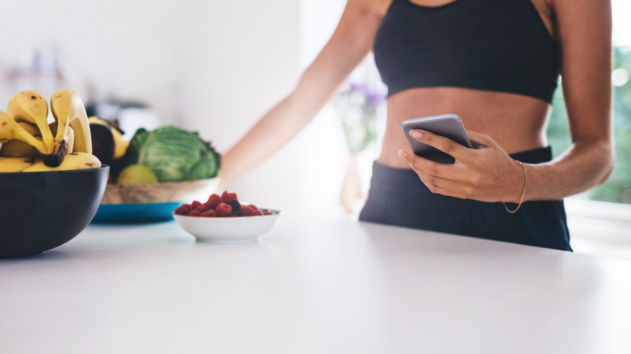 Mulher com celular na cozinha