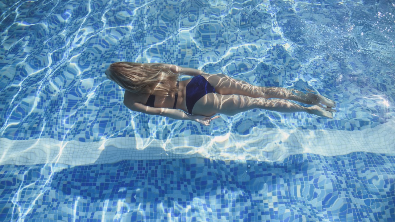 Mulher loira nadando dentro na piscina