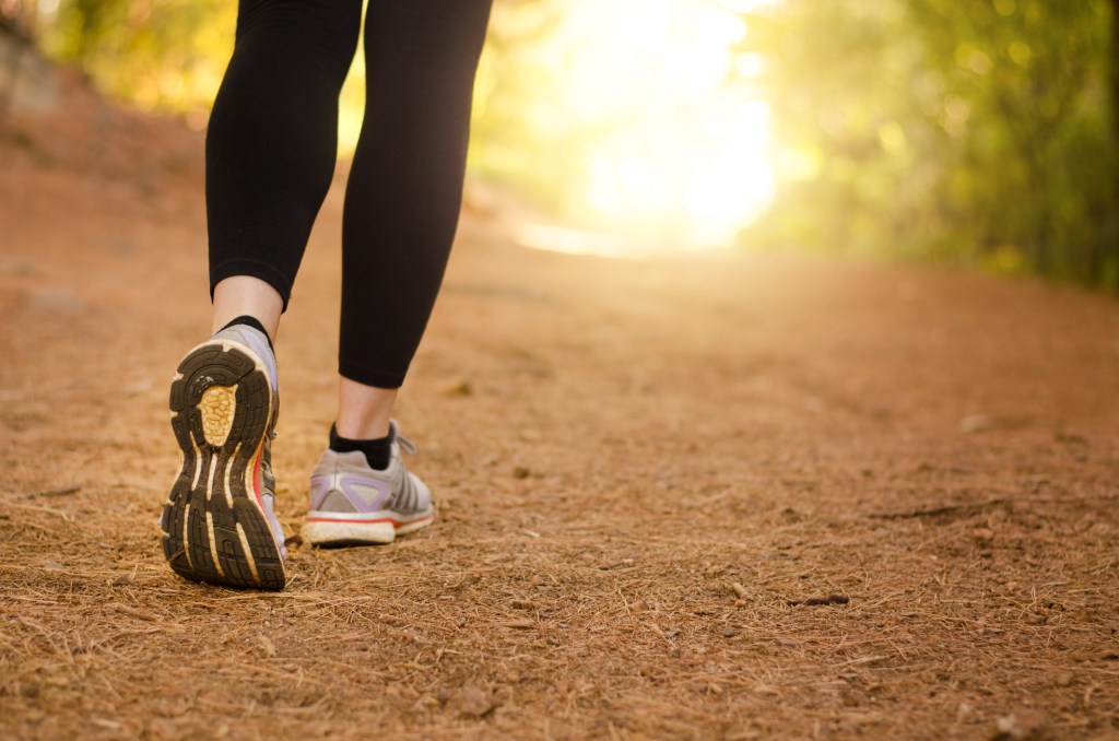 Mulher caminhando no parque com roupa fitness e tênis de corrida