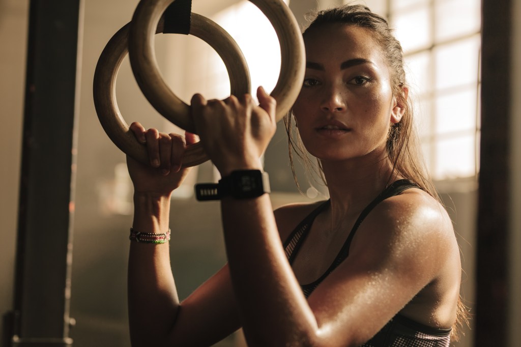 mulher segurando argolas no treino de crossfit enquanto descansa