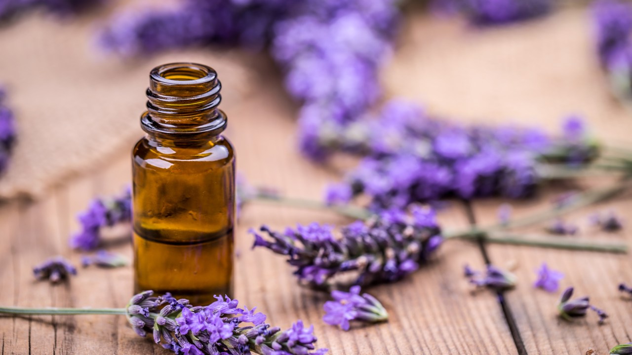 Vidro de frasco âmbar com óleo e flores de lavanda em um piso de madeira