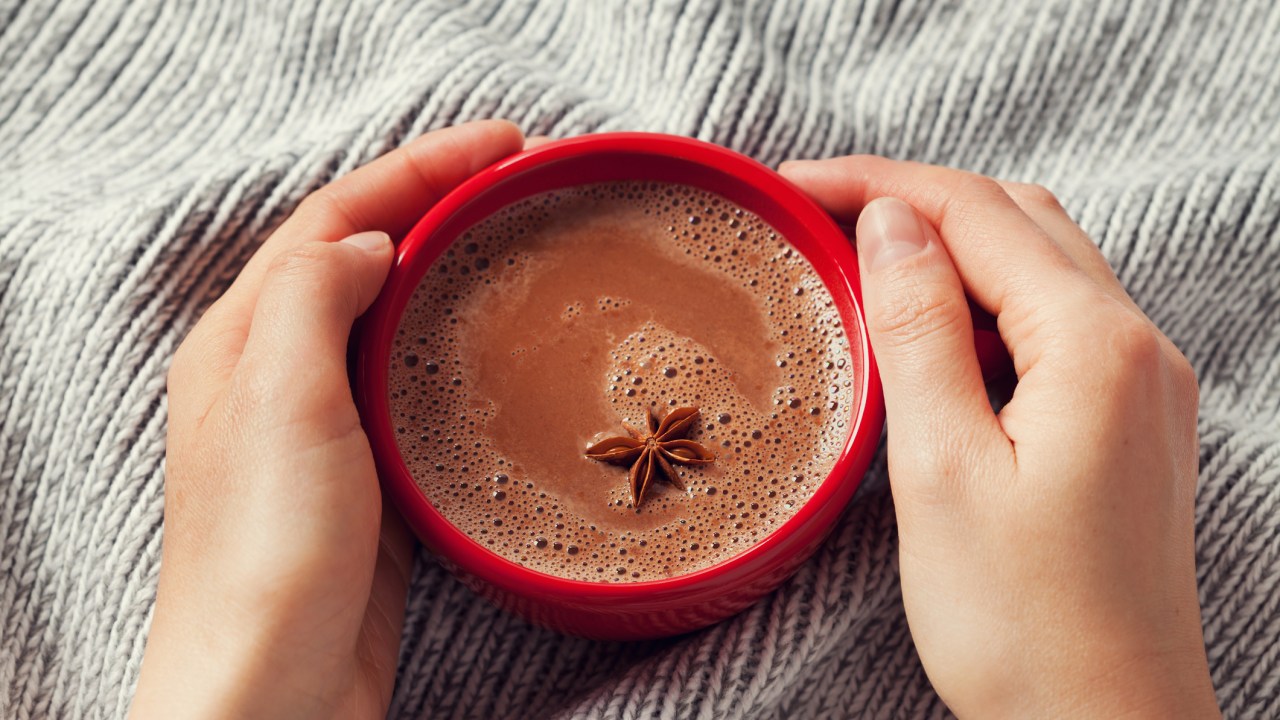 mãos na xícara de chocolate quente