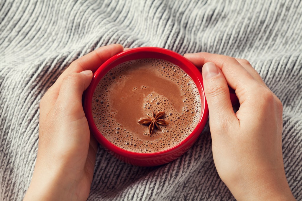 mãos na xícara de chocolate quente