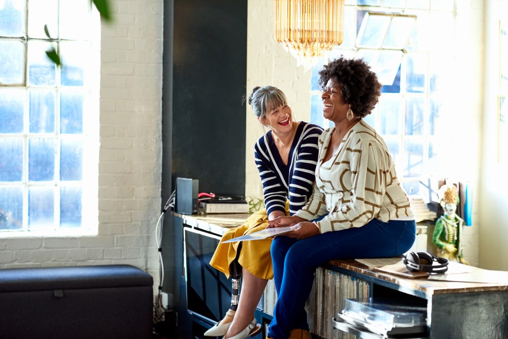 Mature women laughing together in stylish loft apartment como fazer amizades