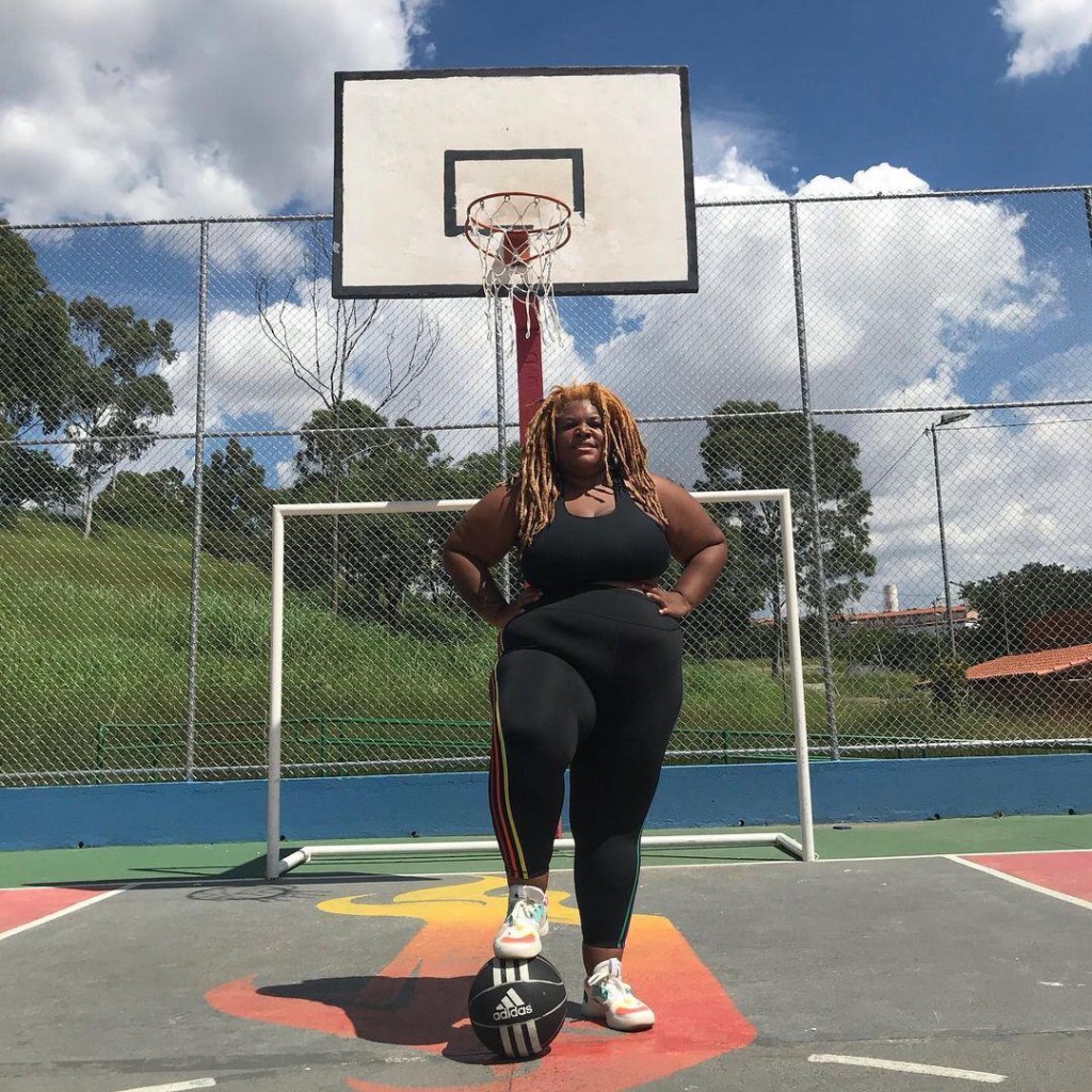 Ellen, atleta de peso, posando para foto em uma quadra de basquete com a bola apoiada no chão