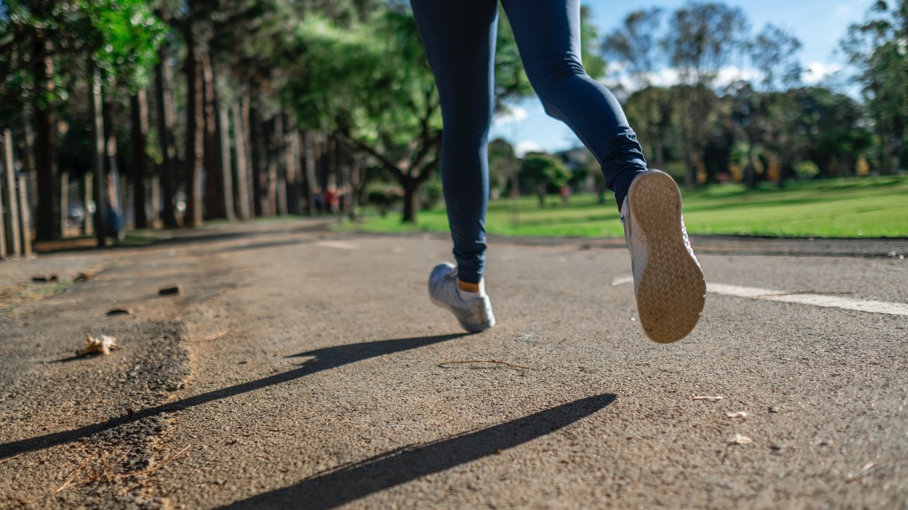 Mulher correndo na rua, em praça - Correr na esteira: Quais as diferenças do asfalto?