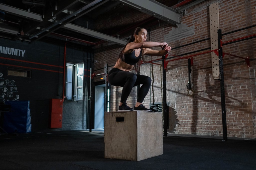 mulher pulando em caixote na academia de crossfit