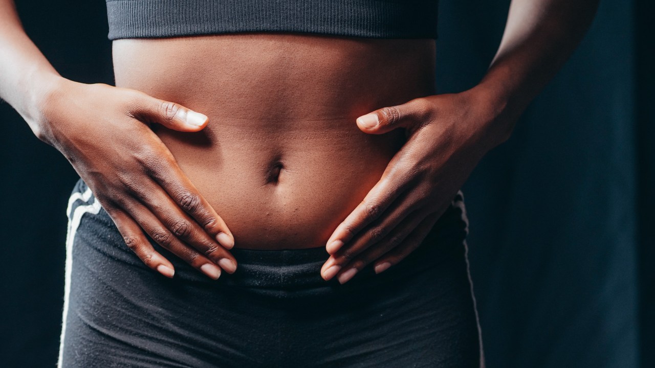 mulher com as mãos na barriga