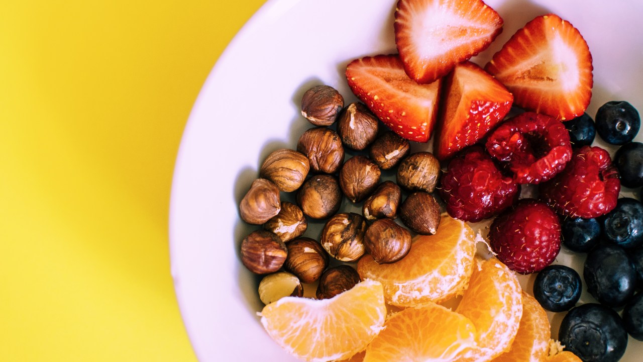 prato com frutas e castanha sobre fundo amarelo