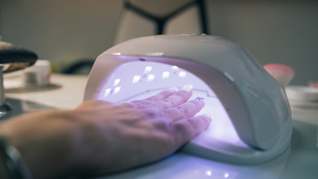 UV lamp gel polish manicure process. Salon procedure. The master coats the client’s nails with a varnish. UV lamp gel polish manicure process. Salon procedure. The master coats the client’s nails with a varnish.