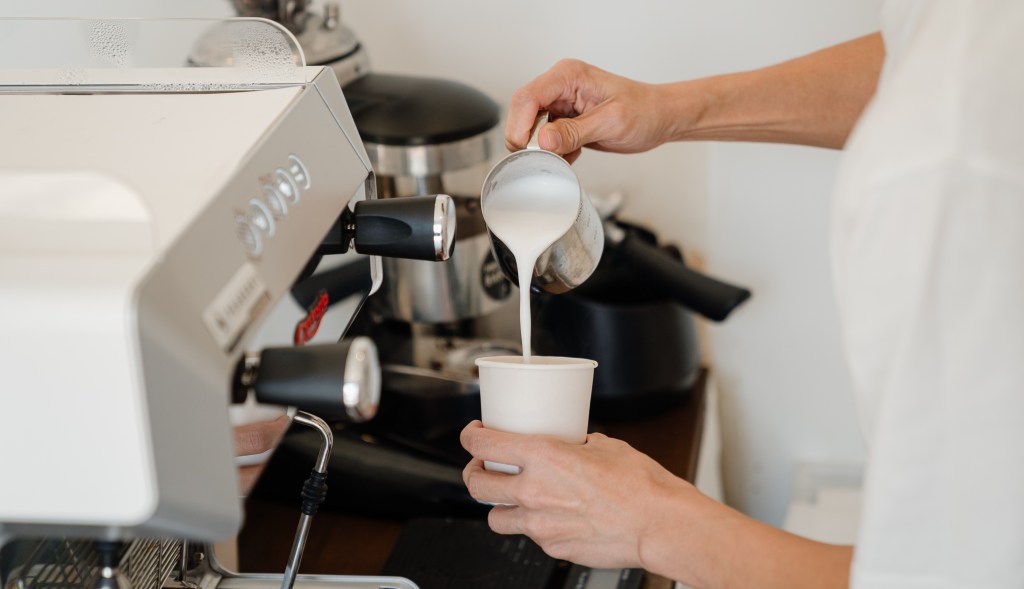 barista despejando leite em uma caneca