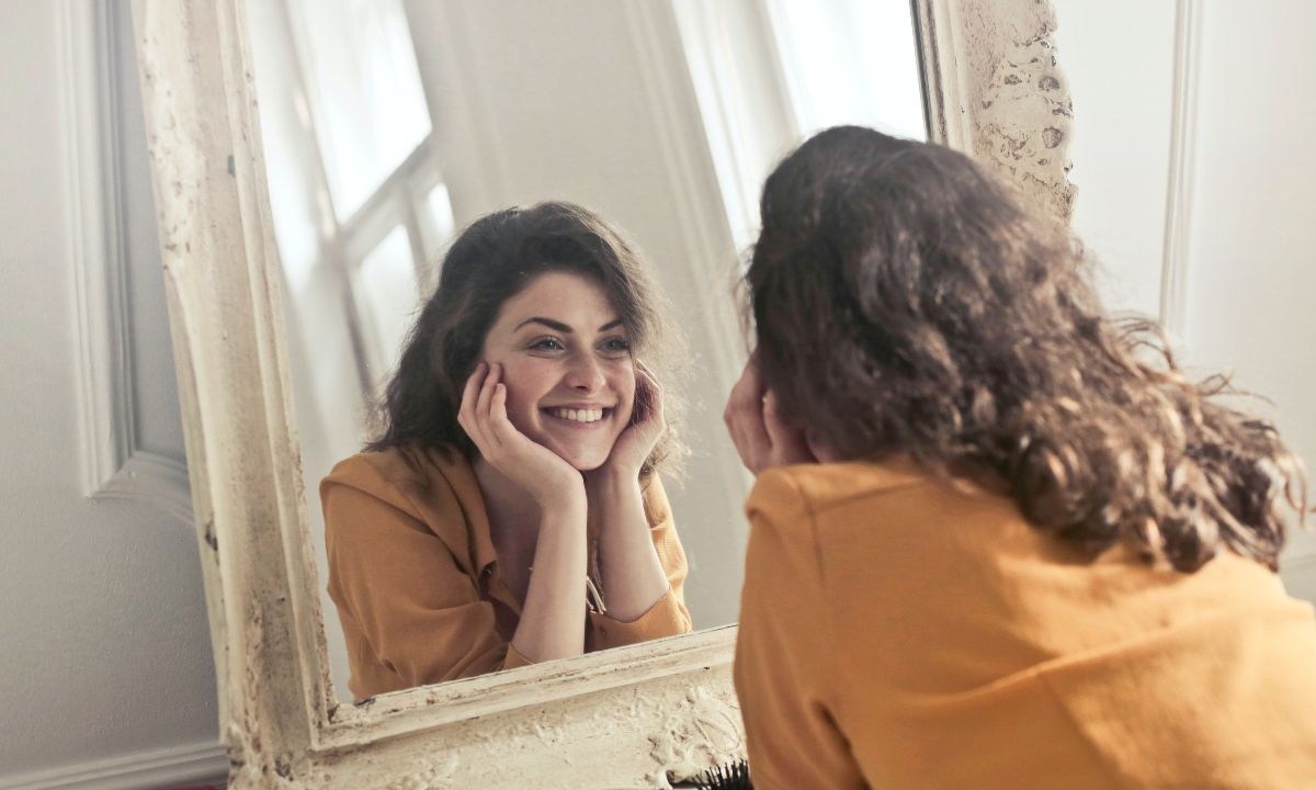 Mulher sorrindo na frente do espelho