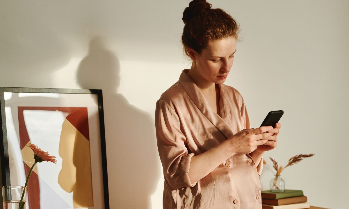 Mulher em pé mexendo no celular