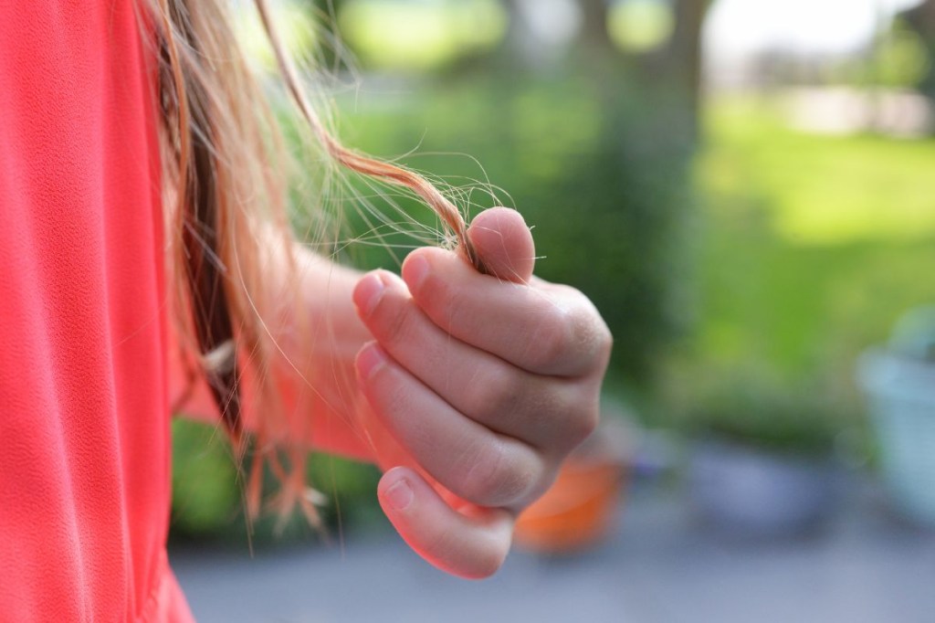 Foco na mão de uma mulher mexendo no cabelo