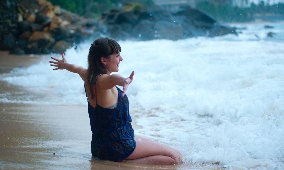 Mulher na beira do mar com os braços abertos