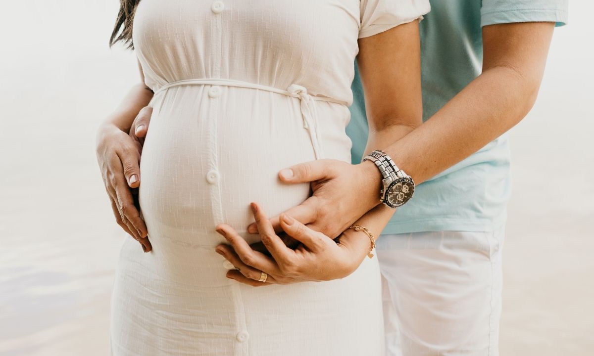 Mulher Grávida Abraçando A Barriga Com O Marido