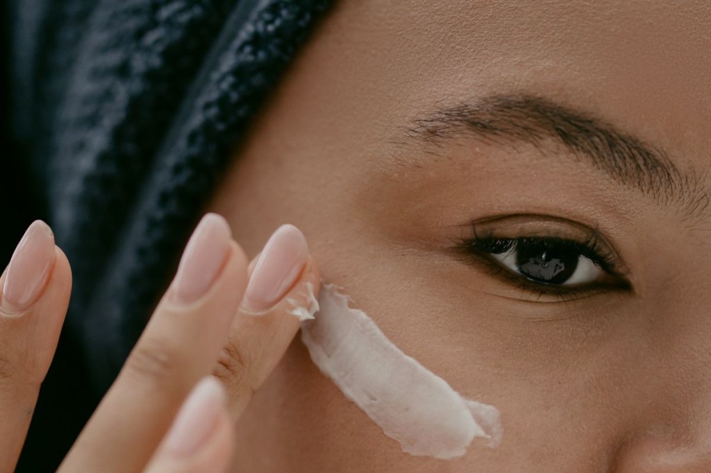 Mulher passando creme na região dos olhos