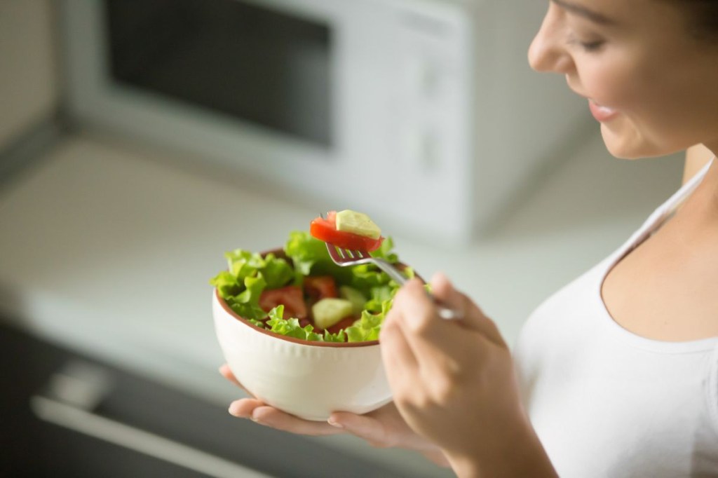 Mulher segurando uma tigela com salada verde