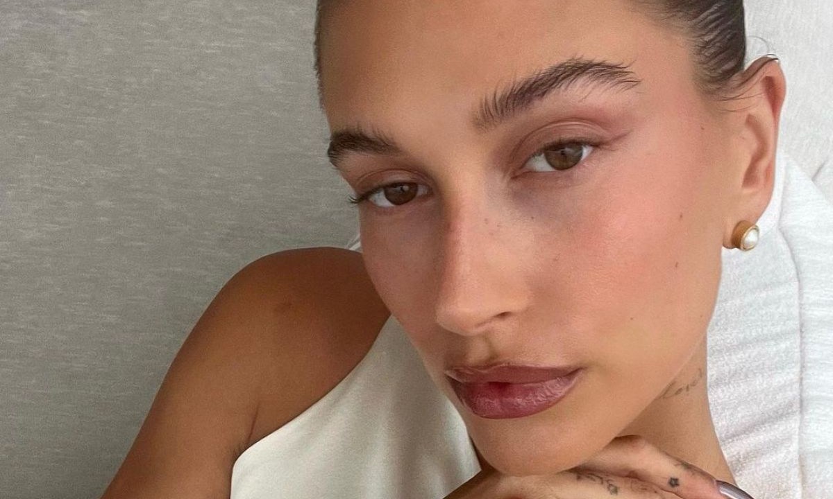 Hailey Bieber com o queixo apoiado na mão