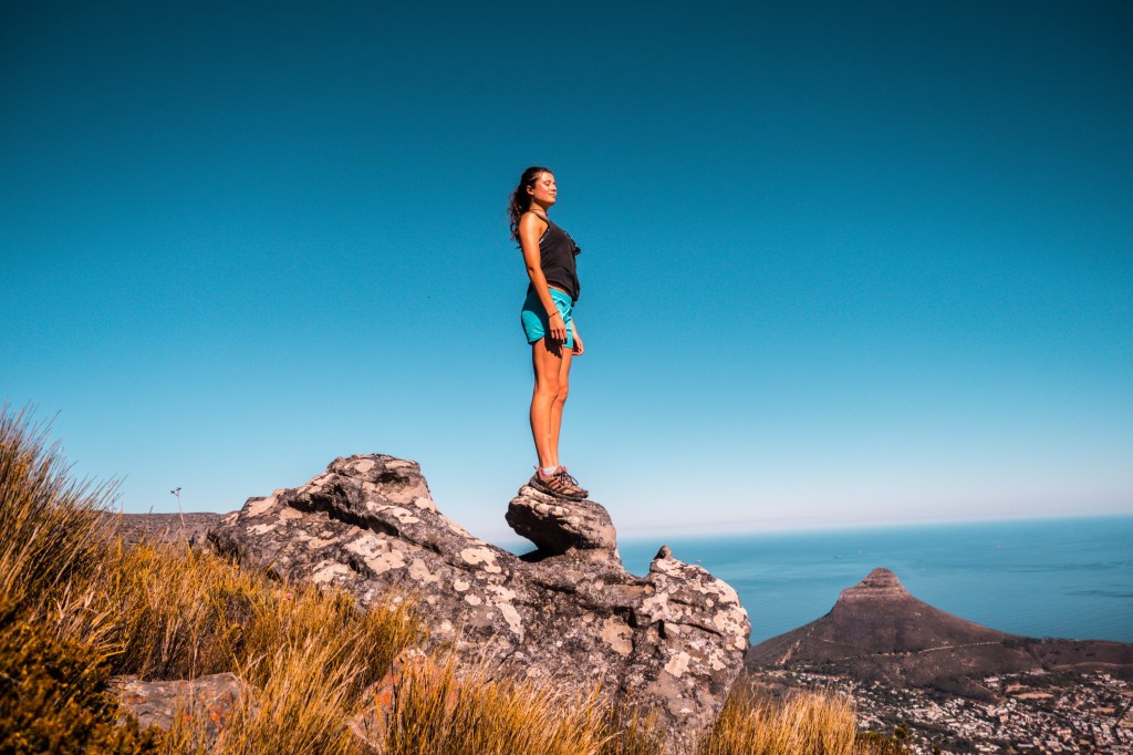 Mulher de pé no alto de uma pedra