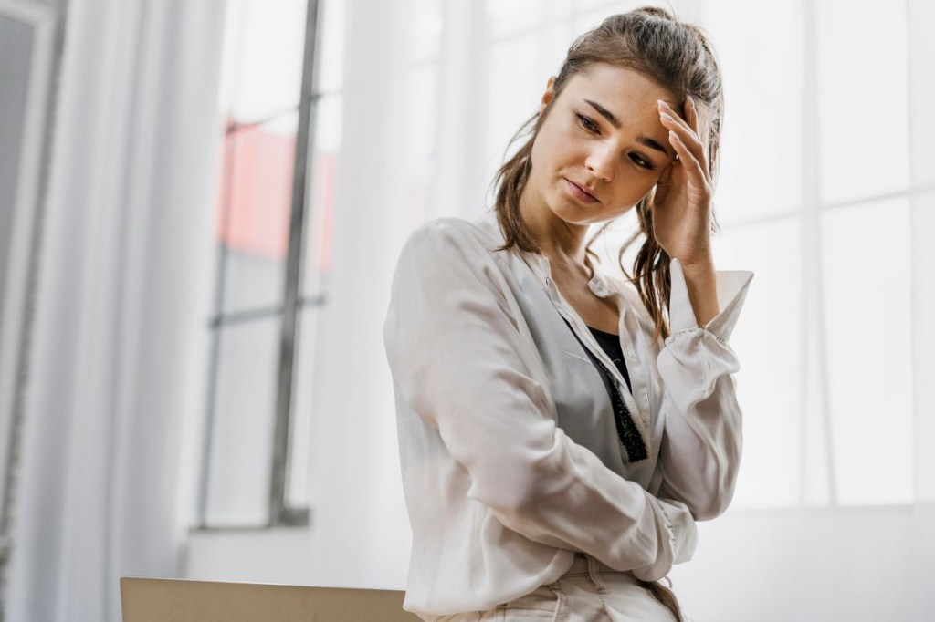 Mulher com a mão na cabeça lidando com dias difíceis