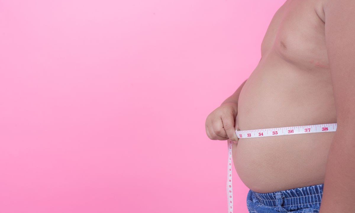 Homem medindo a circunferência abdominal com fita métrica